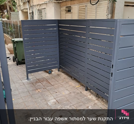 גדר מתכת אפורה מותקנת בחצר בניין